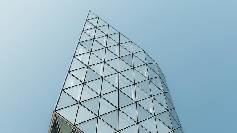 Sommet d'une tour vitrée au dessin triangulaire se découpant sur un ciel bleu