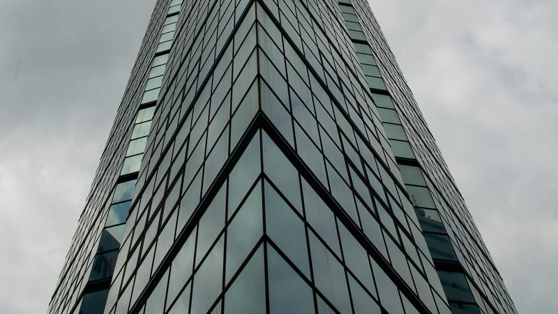Immeuble en verre vu en contre-plongée sous un ciel nuageux dramatique