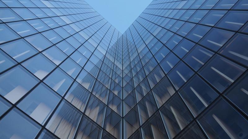 Façade d'immeuble moderne aux lignes verticales sombres se reflétant sur verre