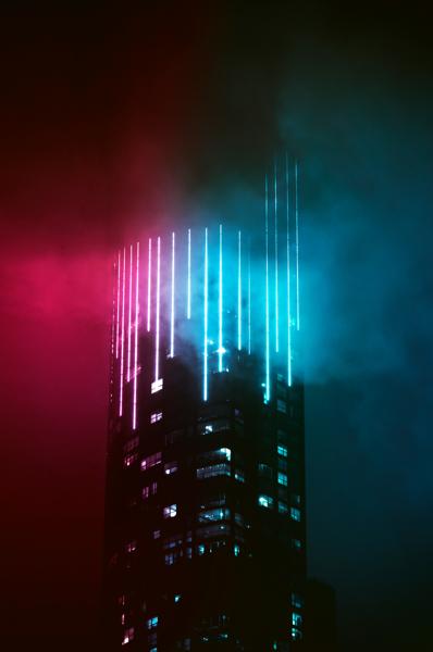 Sommet de tour illuminé de lignes turquoise et rouge dans la nuit