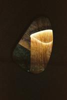Faisceaux de lumière dorée traversant une forme abstraite sombre