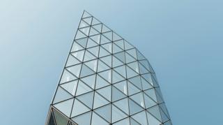 Sommet d'une tour vitrée au dessin triangulaire se découpant sur un ciel bleu