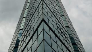 Immeuble en verre vu en contre-plongée sous un ciel nuageux dramatique