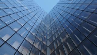 Façade d'immeuble moderne aux lignes verticales sombres se reflétant sur verre